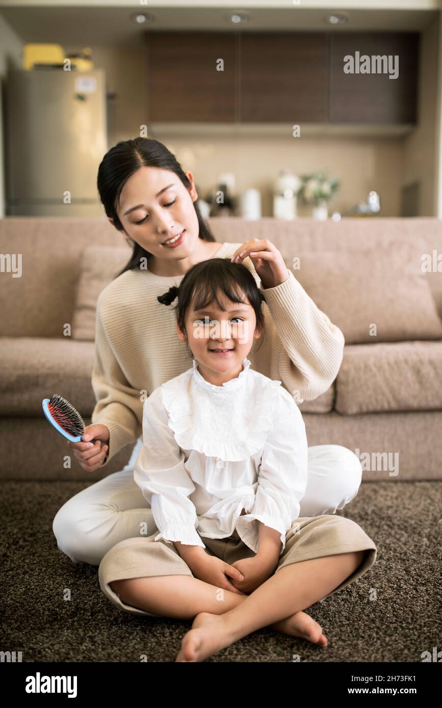 Mother combing her daughter's hair Stock Photo
