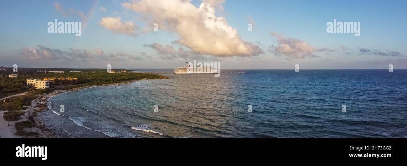 Cozumel, Mexico - February 11, 2020: High angle aerial panoramic shot of Carnival Freedom docked in Costa Maya port. Shore line, splashing waves in th Stock Photo
