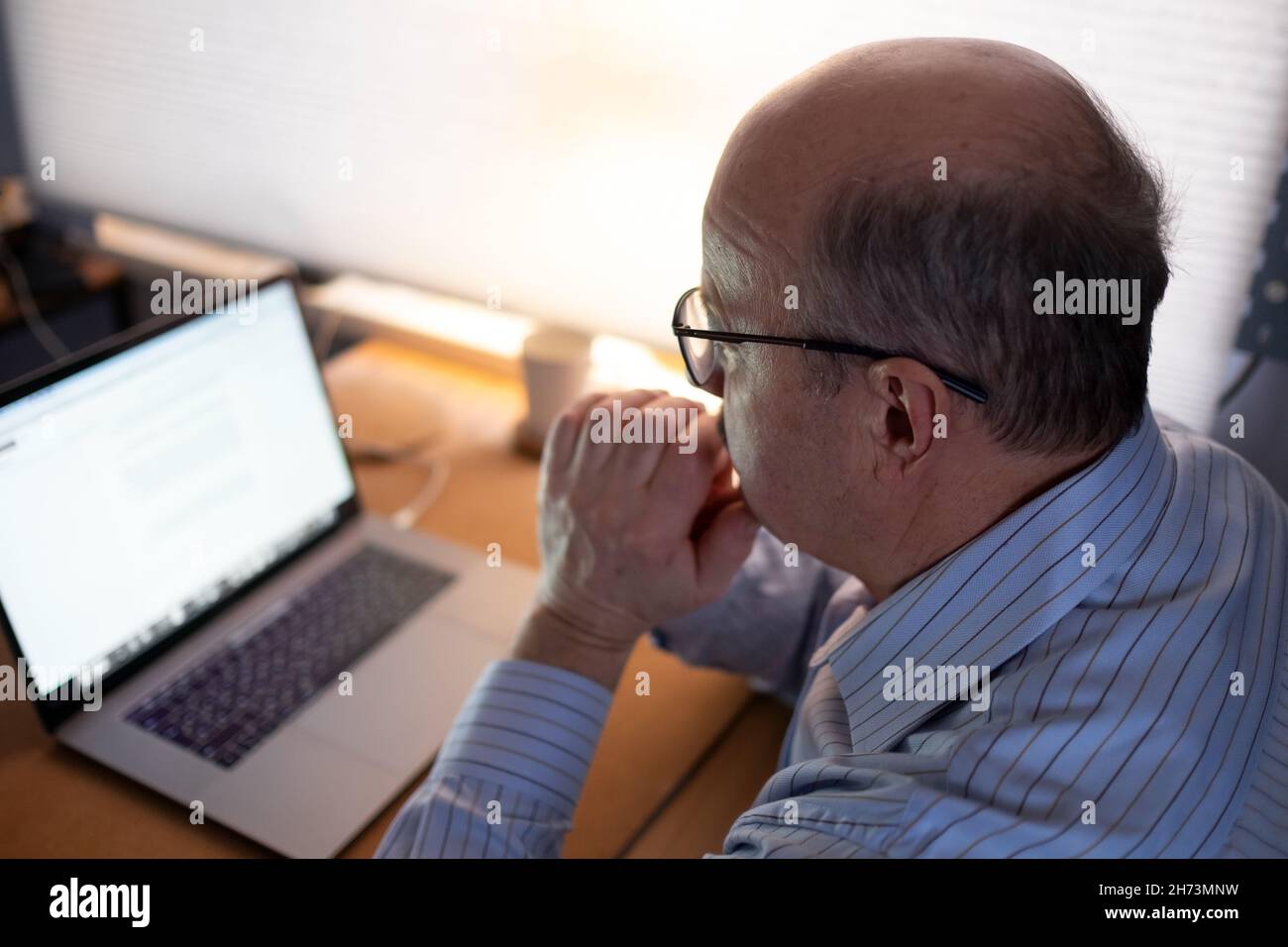 Senior man working with laptop computer at home and thinking on document. Stock Photo