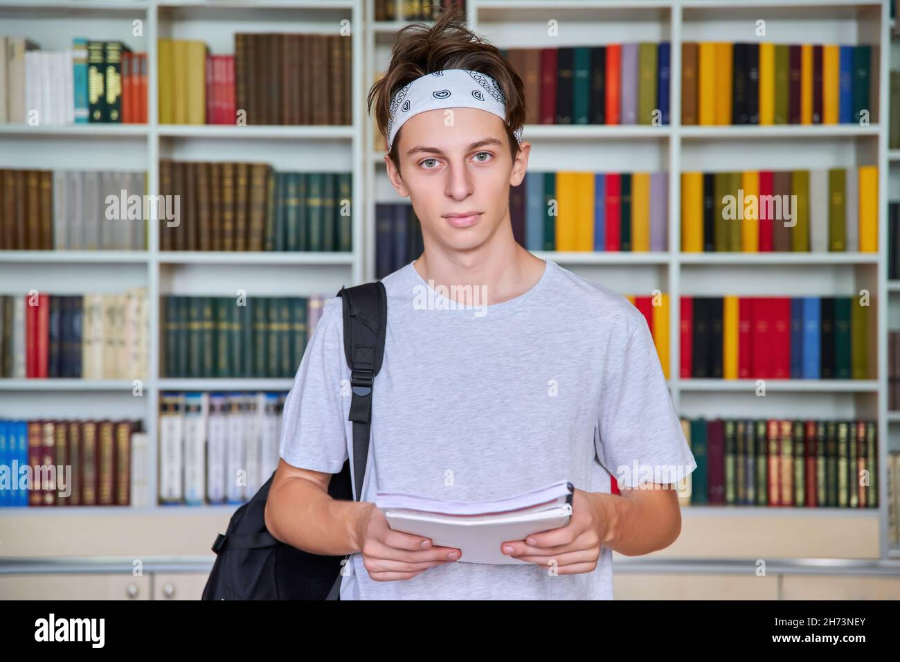 Portrait of a male teenage student looking into the camera in the library. Stock Photo