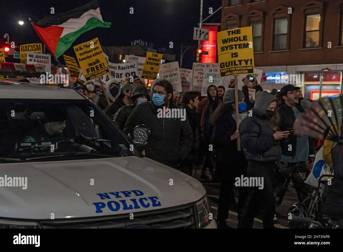 New York, USA. 19th Nov, 2021. Protestors march by an occupied New York Police Department (NYPD) vehicle during a protest march in Brooklyn against the acquittal of Kyle Rittenhouse in New York City.Hundreds march through Brooklyn to protest Rittenhouse verdict and calling his acquittal a double standard and a failure of the justice system. Kyle Rittenhouse (18) faced homicide charges and other offenses in the fatal shootings of Joseph Rosenbaum and Anthony Huber and for shooting and wounding of Gaige Grosskreutz during unrest in Kenosha that followed the police shooting of Jacob Blake in Augu Stock Photo