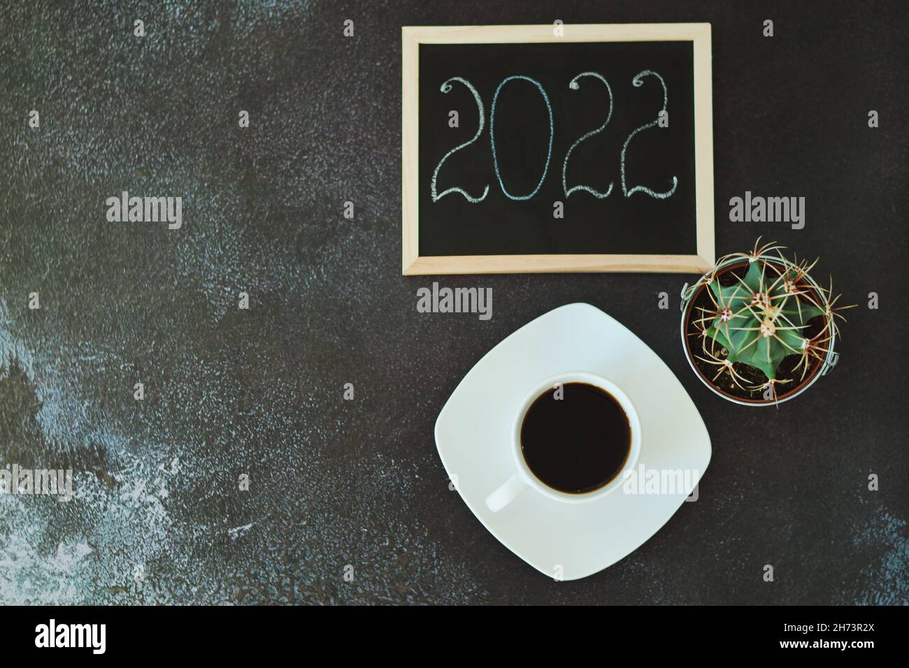 Christmas, New Year flat lay on black background. Christmas decorations with cup of hot coffee. Numbers 2022 on a writing board. Cacti. Top view Stock Photo