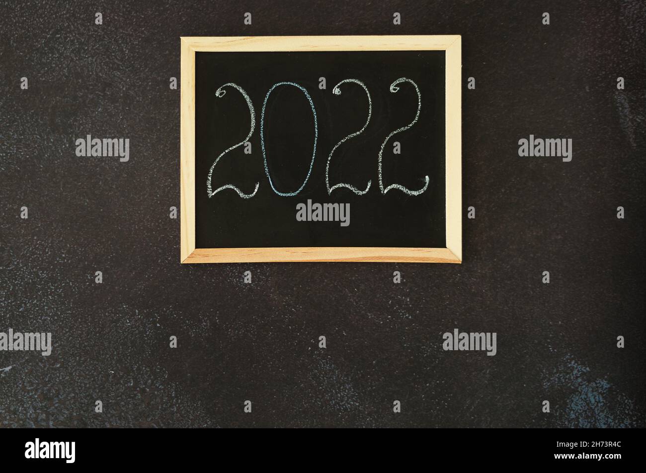 Christmas, New Year flat lay on black background. Christmas decorations with cup of hot coffee. Numbers 2022 on a writing board. Cacti. Top view Stock Photo