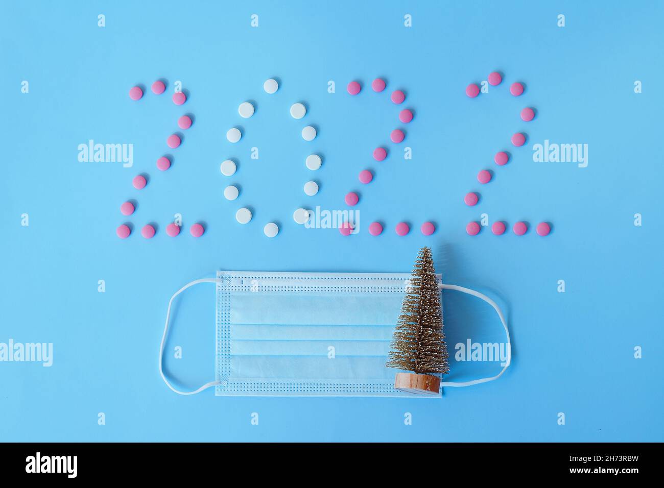 Christmas, New Year flat lay on blue background with place for text. numbers 2022 making with pills and medical mask. Top view. Copy space. Mock up. Stock Photo