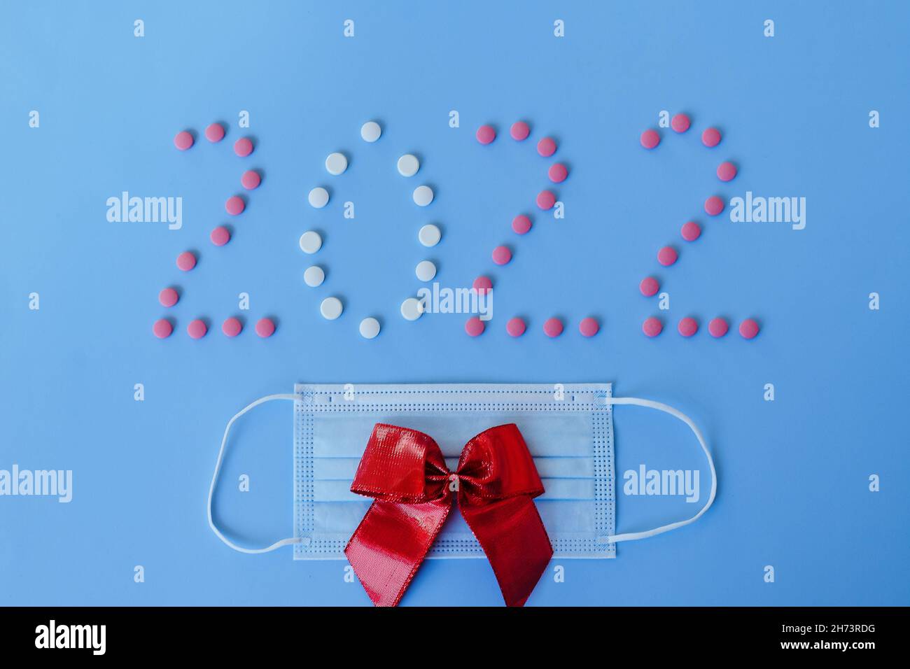 Christmas, New Year flat lay on blue background with place for text. numbers 2022 making with pills and medical mask. Top view. Copy space. Mock up. Stock Photo