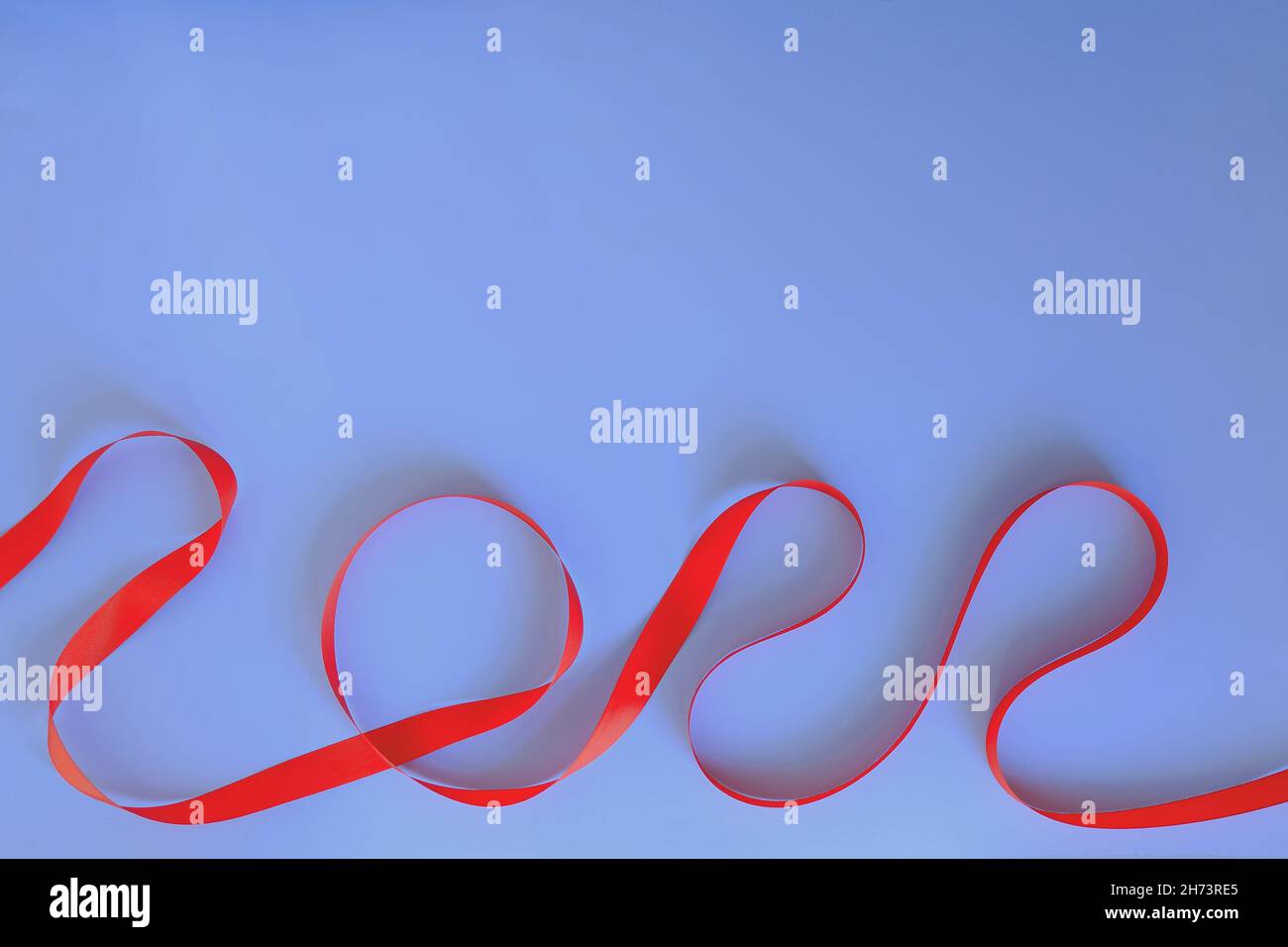 Christmas, New Year flat lay on blue background. Numbers 2022 making with red ribbon. Top view. Copy space. Mock up. Creative ideas of holiday Stock Photo