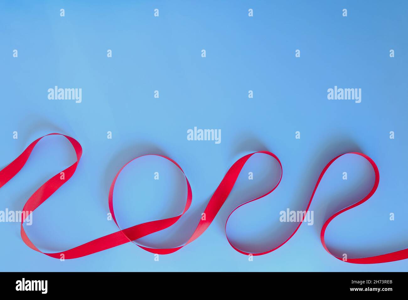 Christmas, New Year flat lay on blue background. Numbers 2022 making with red ribbon. Top view. Copy space. Mock up. Creative ideas of holiday Stock Photo