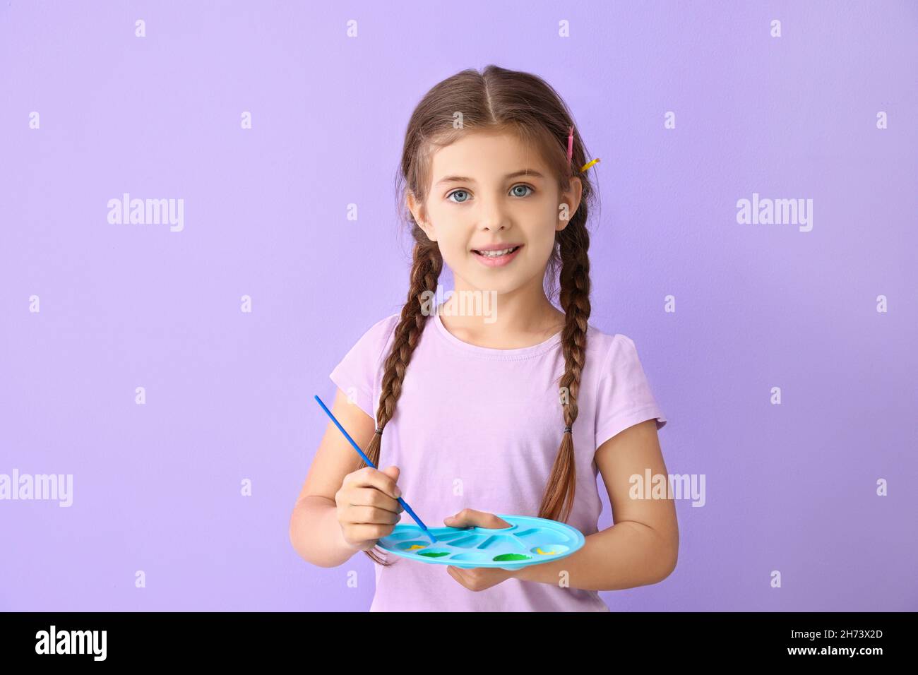 Cute little girl with paint palette and brush on lilac background Stock ...