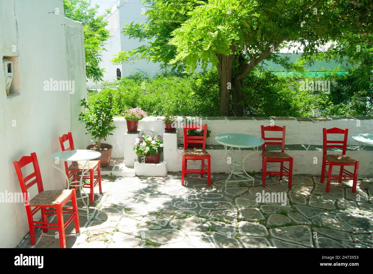 Folegandros island, Greece. Bright red chairs on a shaded terrace in the old village.  Typical Greek scenery.  Landscape aspect shot. Stock Photo
