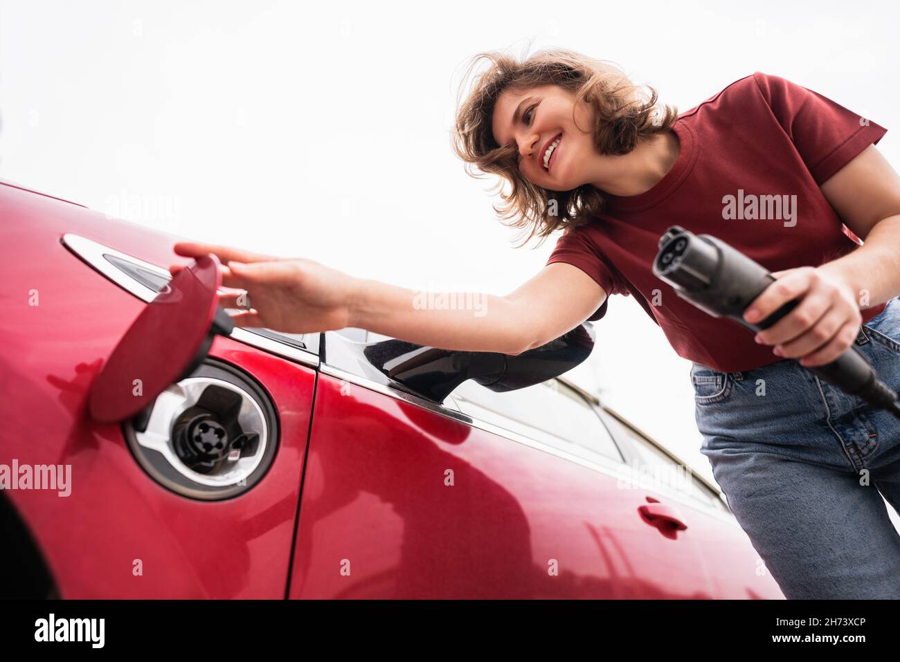 Woman holds a charging plug for an electric car and opens the charging