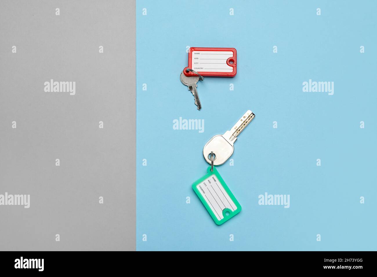 Keys with plastic tags on blue and grey background, top view Stock Photo