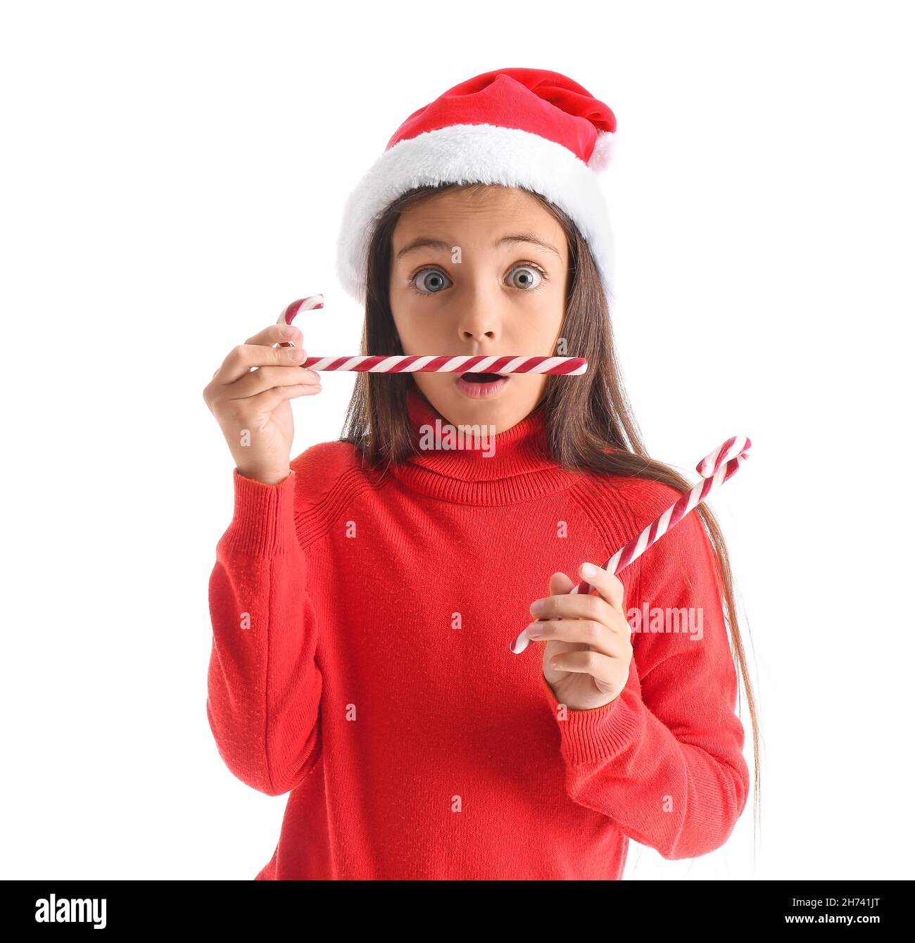 Surprised little girl in Santa hat and with candy canes on white