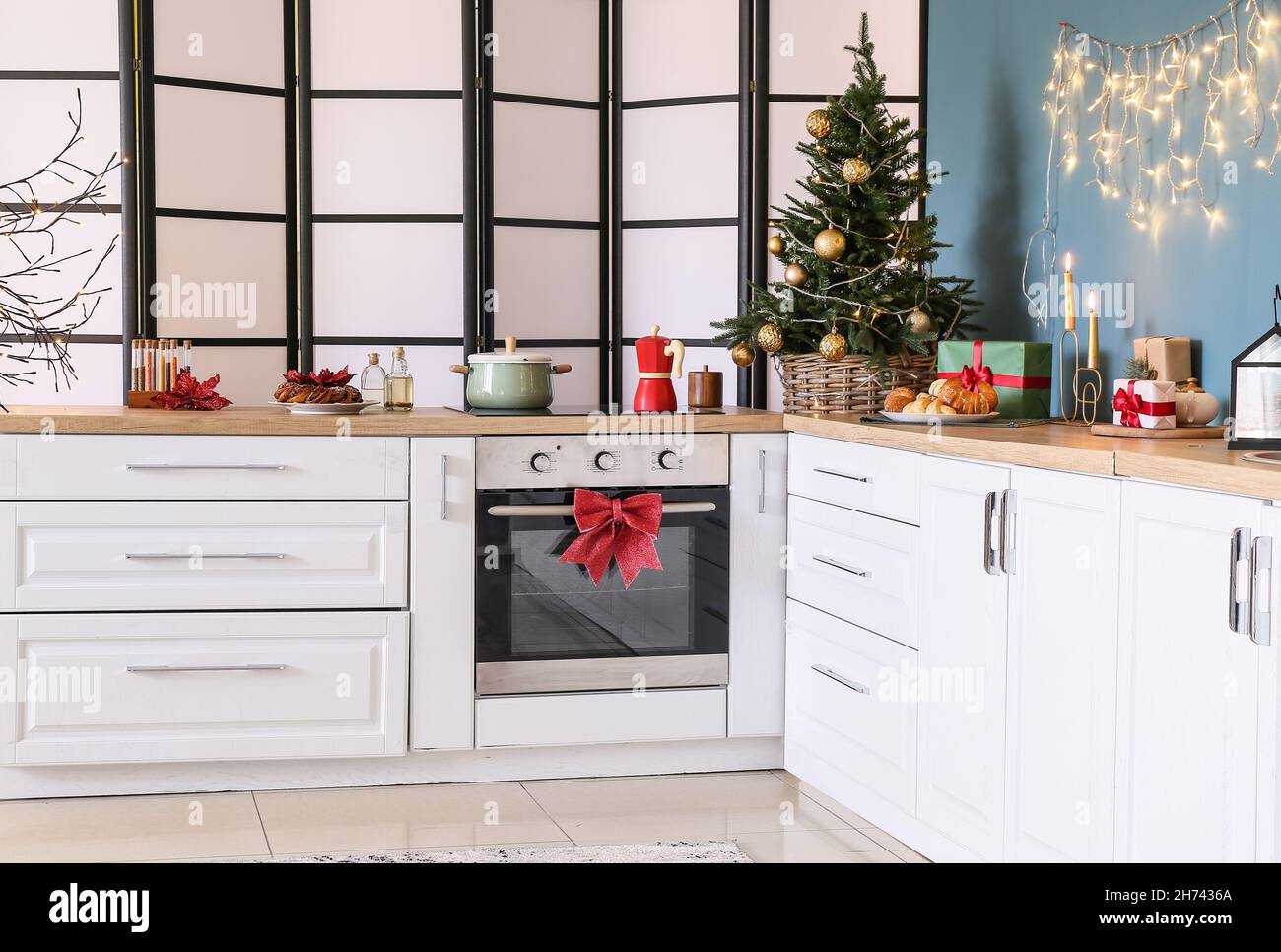 Interior of stylish kitchen with white counters, small Christmas tree