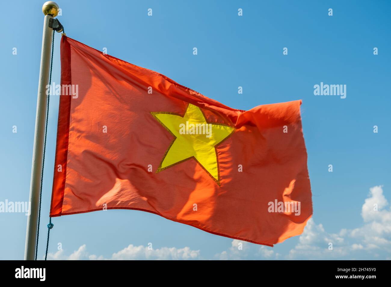 Close up of the red Vietnam National Flag with a gold star in the middle, flying in the sky Stock Photo