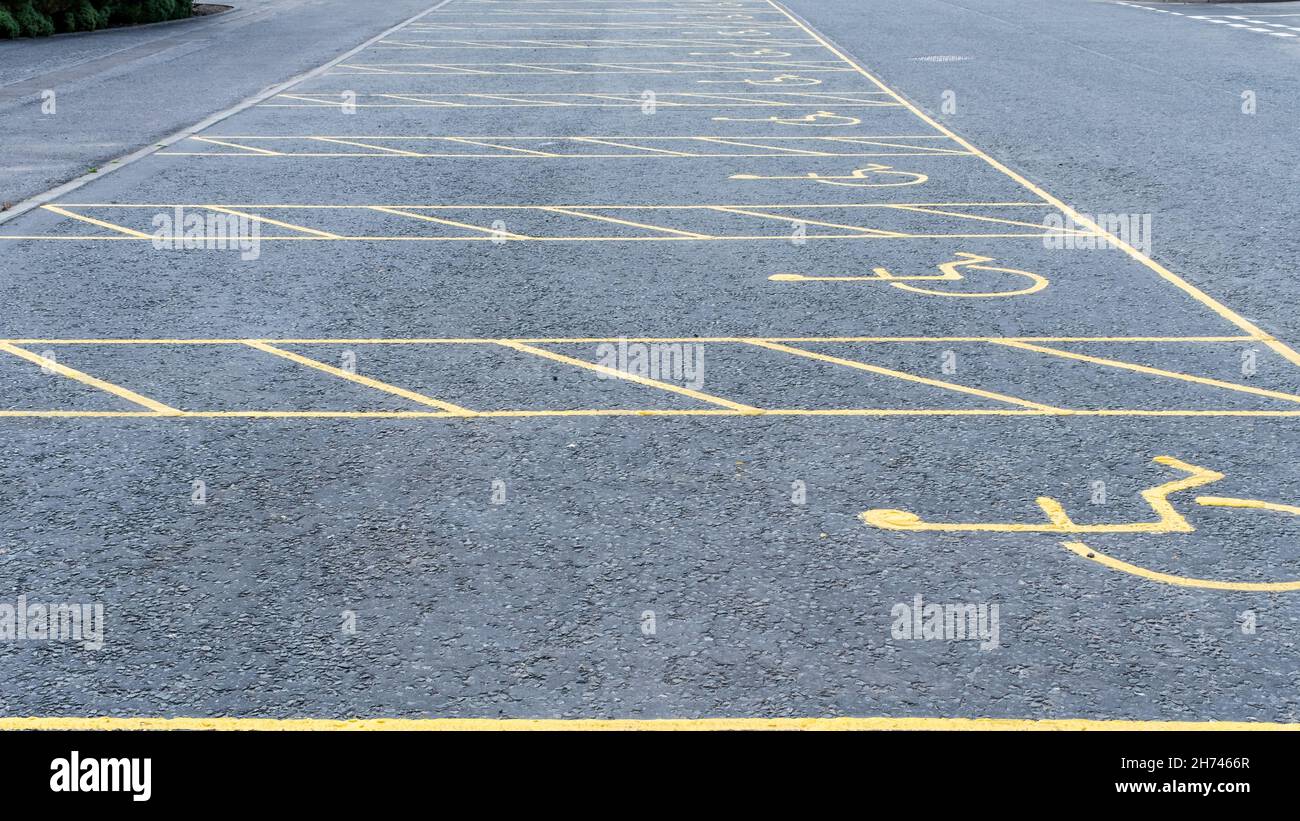 Numerous empty yellow marked disable vehicle parking spaces in a car park Stock Photo