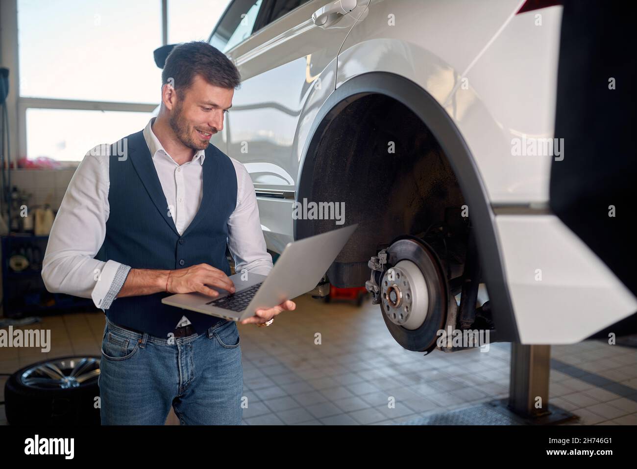 Mechanic Using Laptop While Examining Car Engine. Fixing Stock Photo