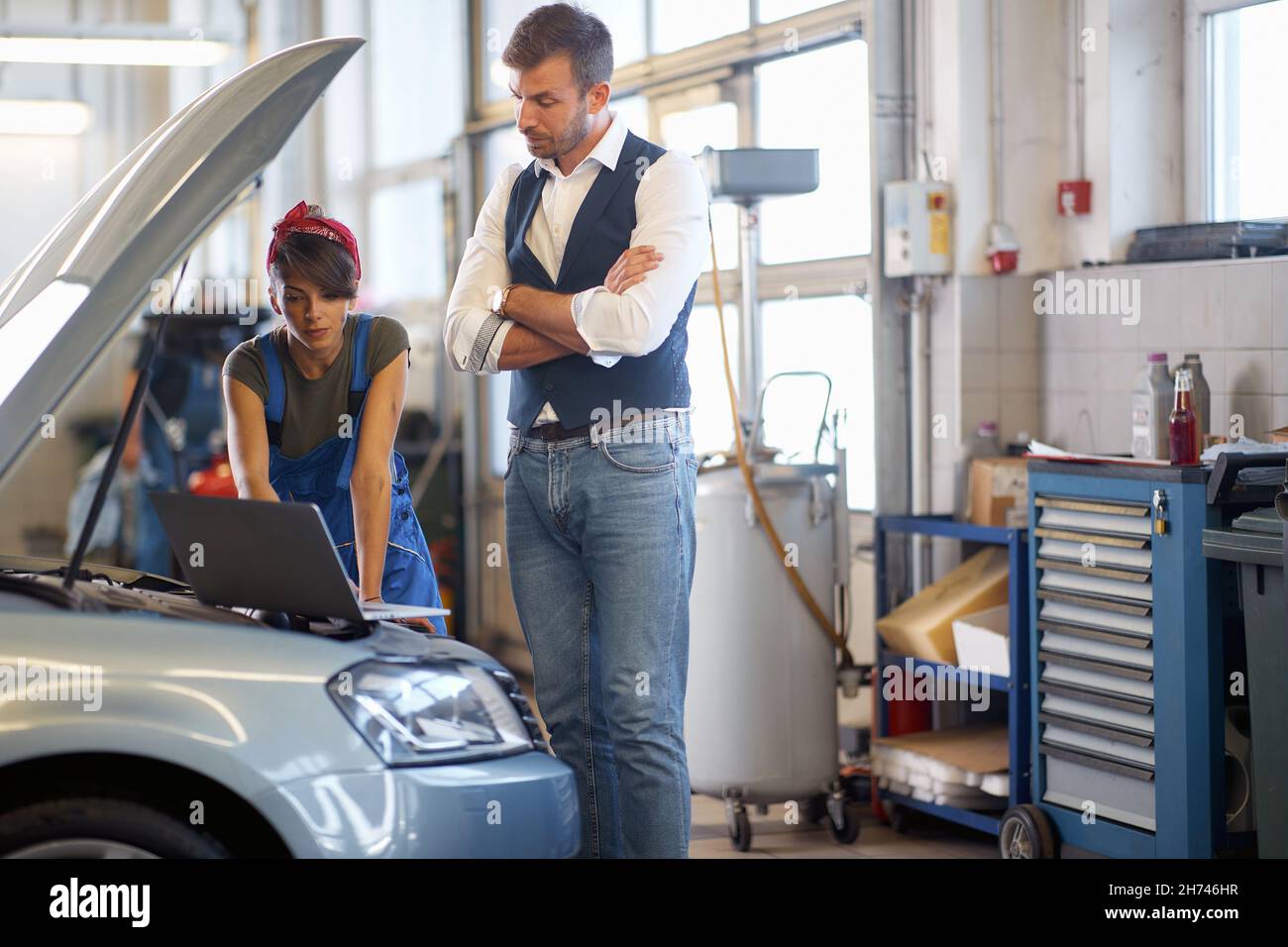 female mechanic with a customer checking a car breakdown on a laptop Stock Photo