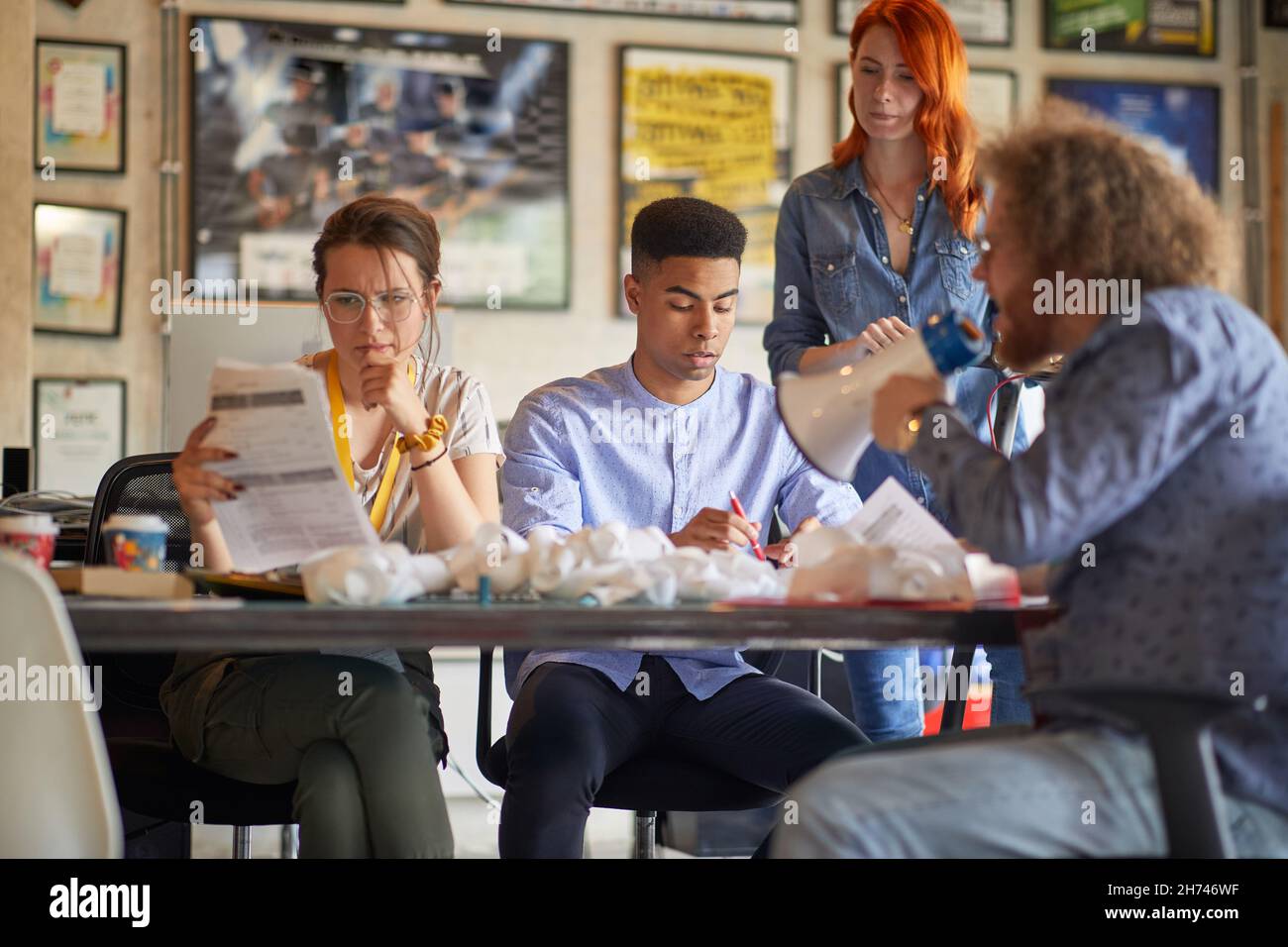 multiethnic group of colleagues working together, while mean boss is yelling on them using megaphone. mobbing concept Stock Photo