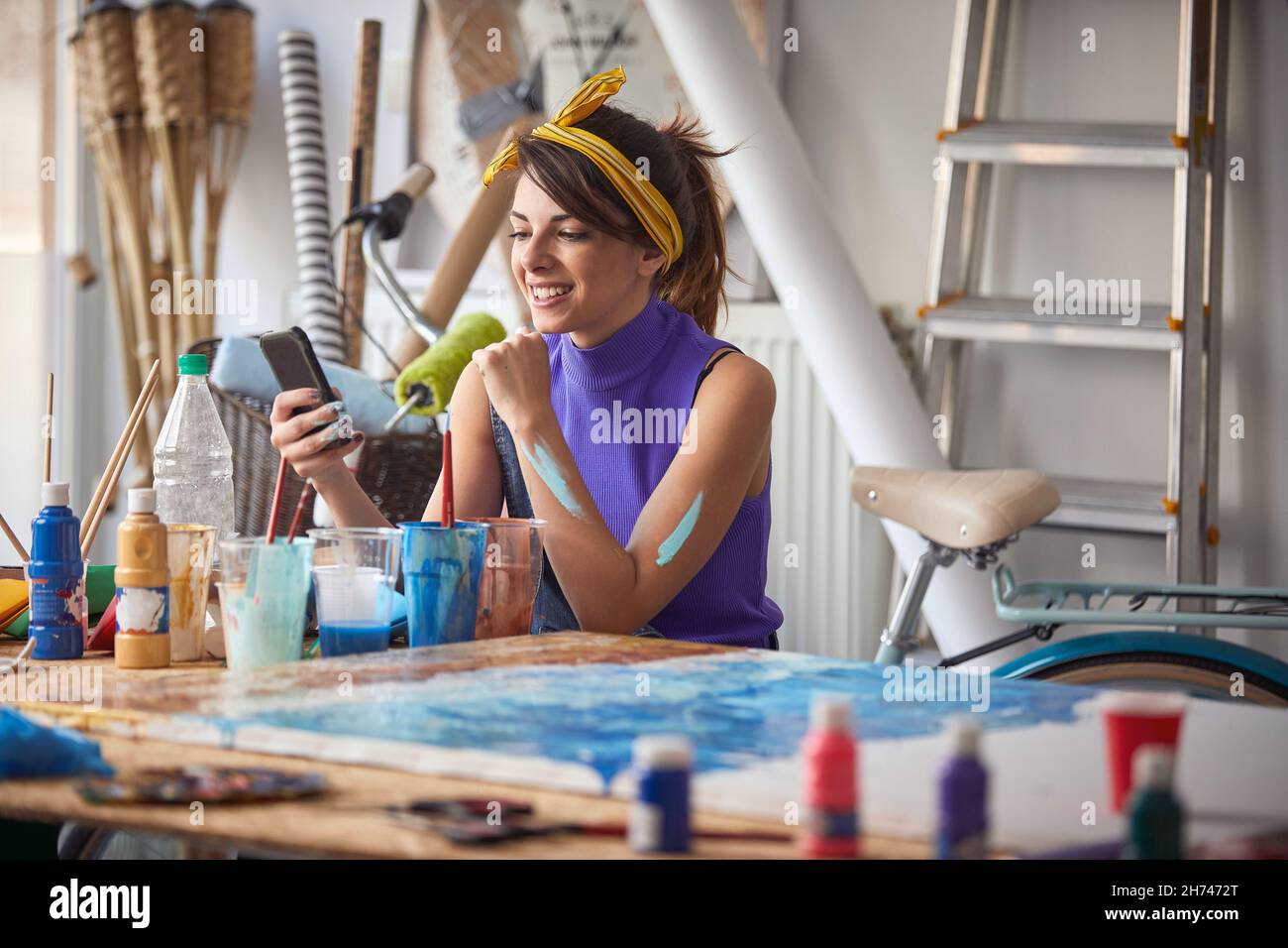 Young female artist using mobile in art studio Stock Photo