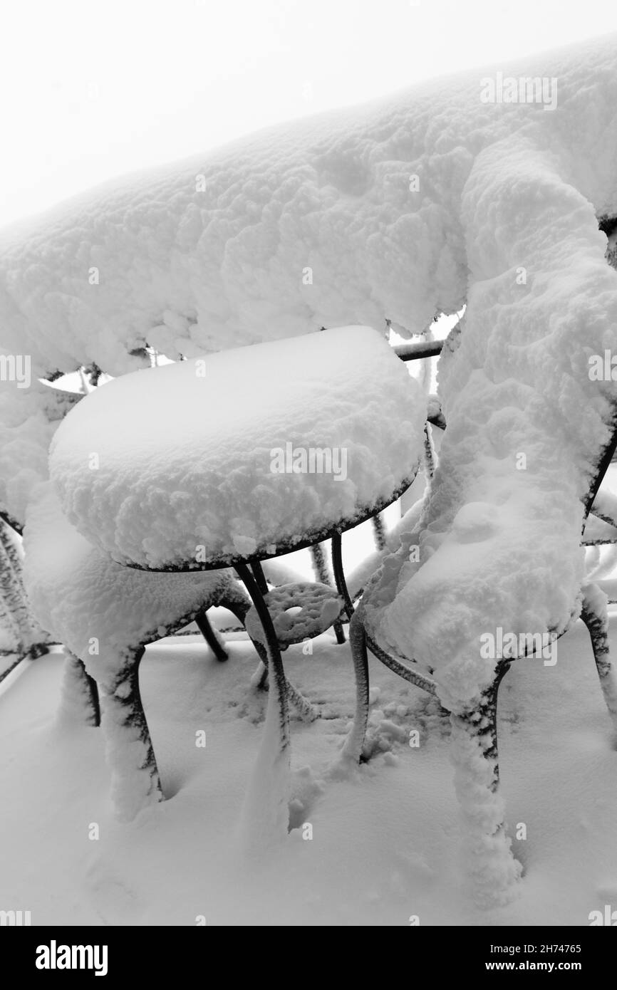 Huge amount of snow on garden furniture on the terrace after blizzard. Natural disasters caused by heavy snowfall, frost and freezing rain. Stock Photo