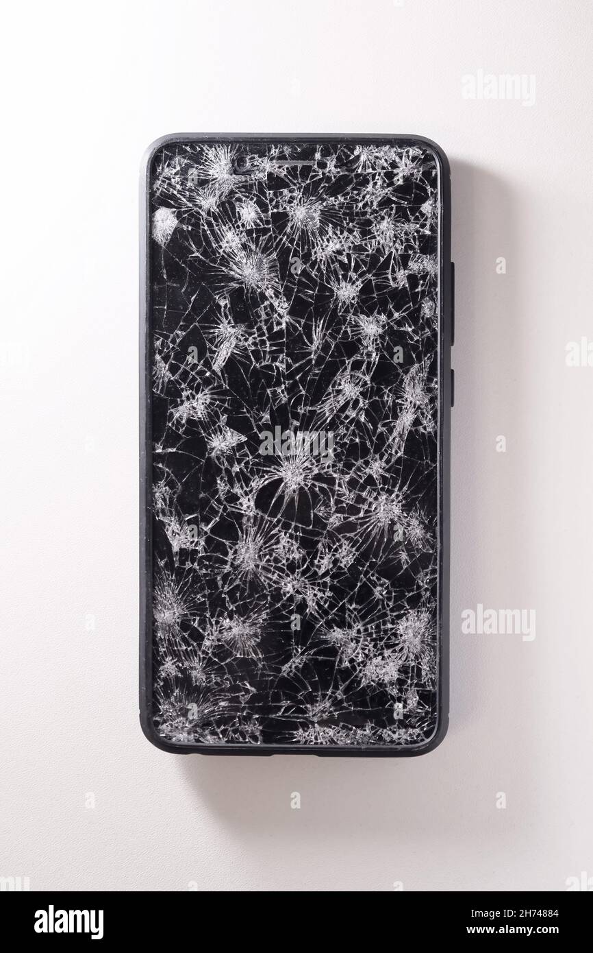 Modern touch screen smartphone with broken screen full of cracks on white background. Repair gadget concept Stock Photo