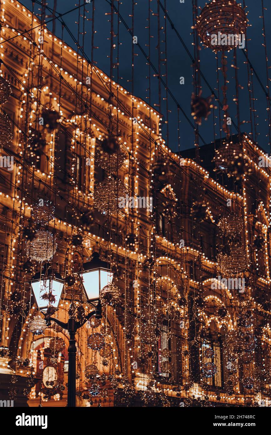 Vintage building decorated with golden glittering festive garlands. Christmas and New Year in the evening city Stock Photo