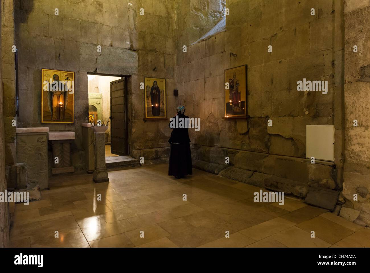 Woman in black clothes praying in front of an icon in the Svetitskhoveli Cathedral. Mtskheta-Mtianeti province, Georgia, Caucasus Stock Photo