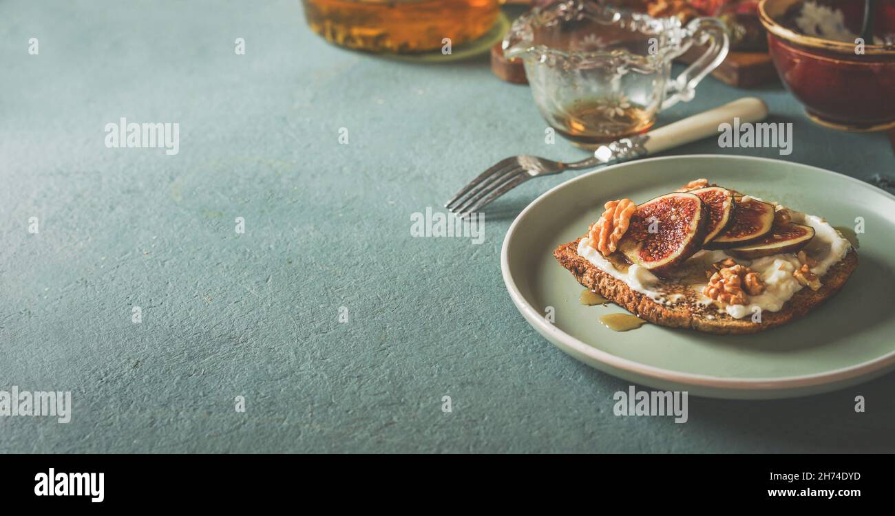 Breakfast background with french toast with creme cheese, figs and honey on plate with kitchen utensils on pale blue kitchen table. Healthy snack at h Stock Photo