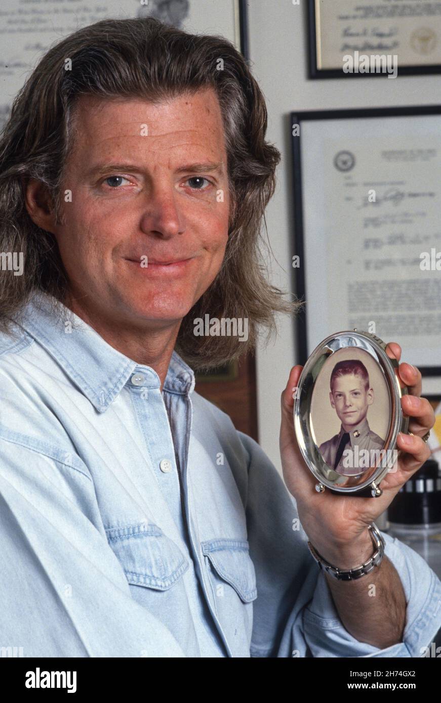 1990s Middle Aged man with Long Hair Holds a 7th Grade school Class Photo of Him with a Crewcurt , USA Stock Photo