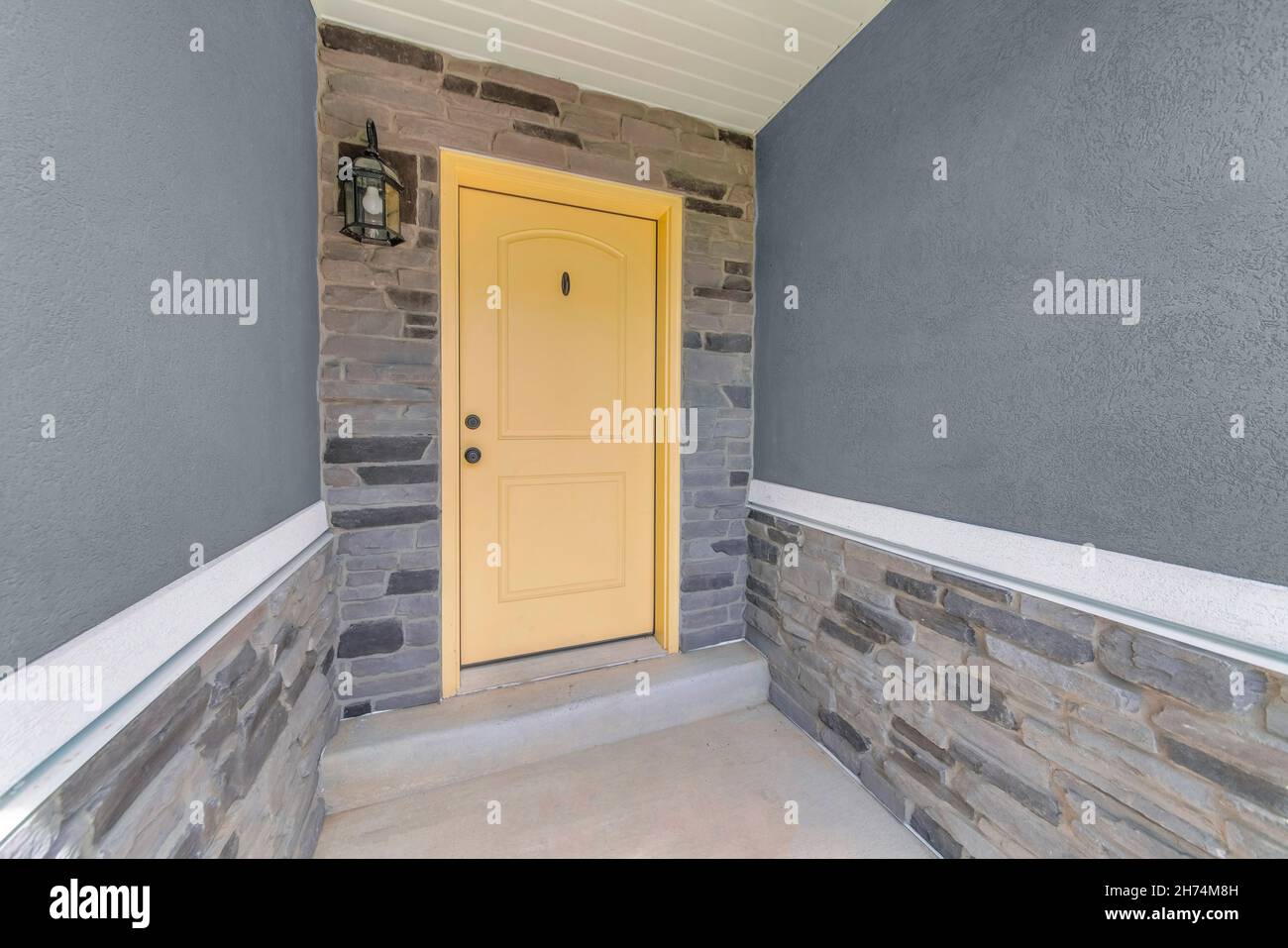 Exterior of an entrance of a house with yellow front door and gray