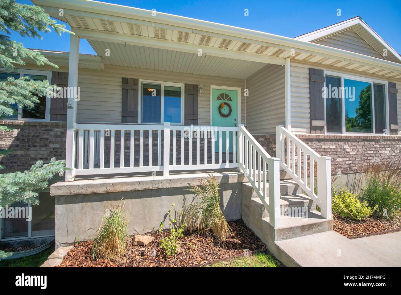Elevated front porch with concrete doorsteps, mint green door and white