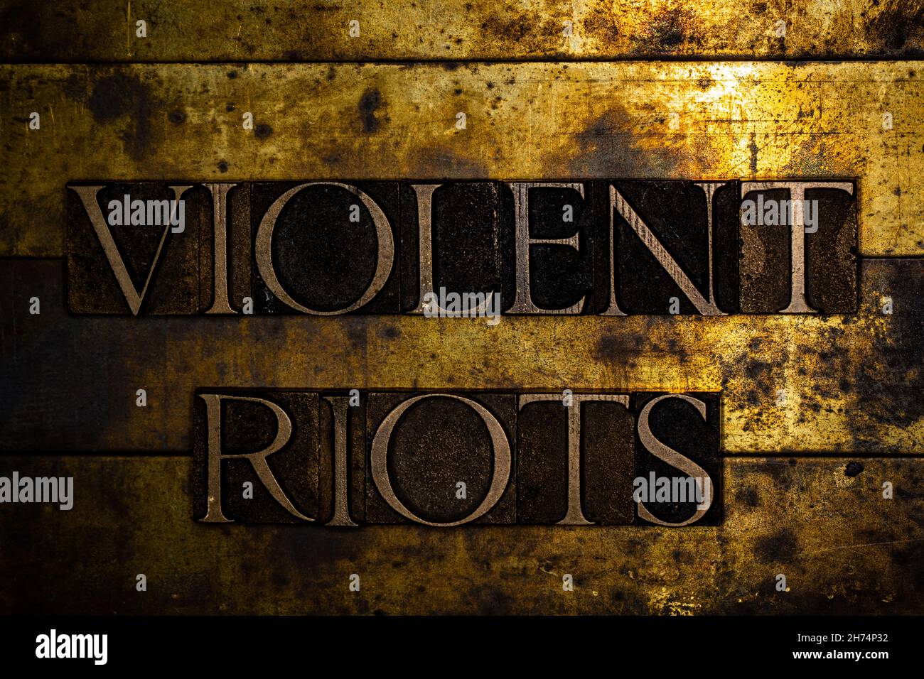 Violent Riots text message on textured grunge copper and vintage gold background Stock Photo