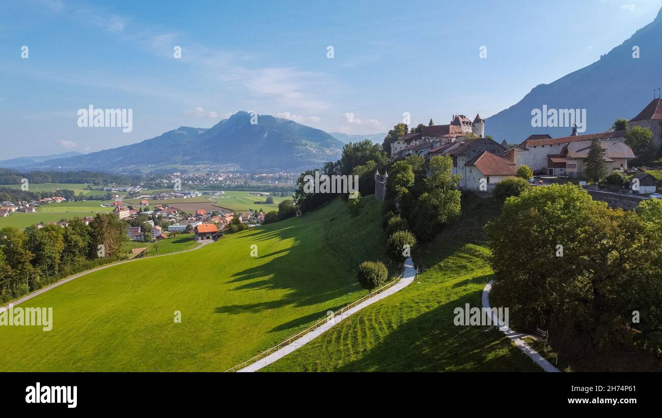 Aerial view of the countryside around the old town of Gruyeres, with the small city of Bulle and the mountains in the background. Gruyeres, Friburgo, Stock Photo