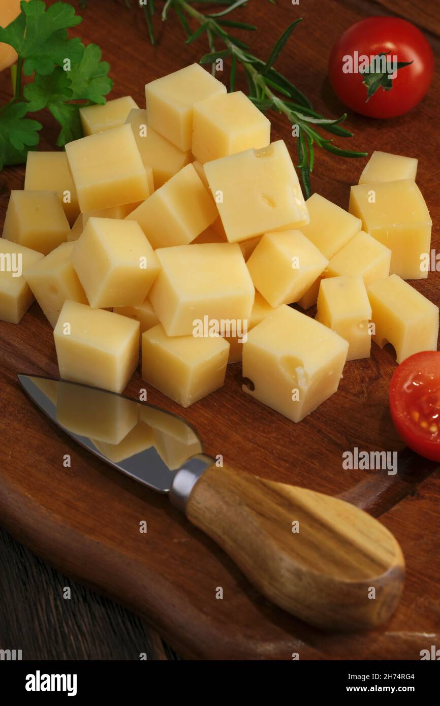 Close-up shot of cheese slices with knife on rustic wooden table Stock Photo