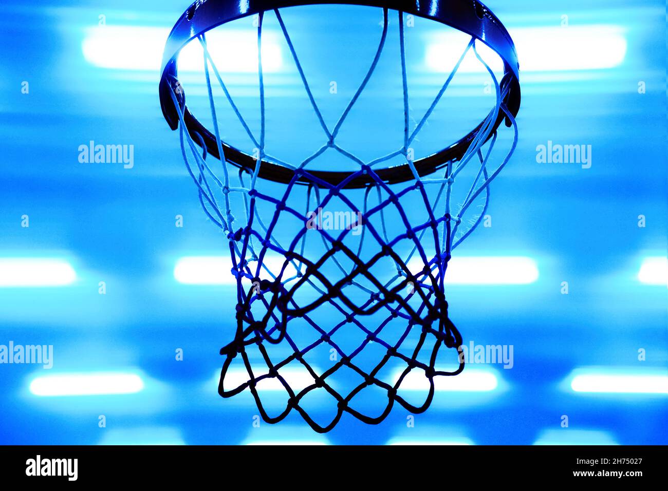 Basketball hoop against background of bright spotlights on ceiling. Bottom view. Sporty back. Blue Neon color. Stock Photo