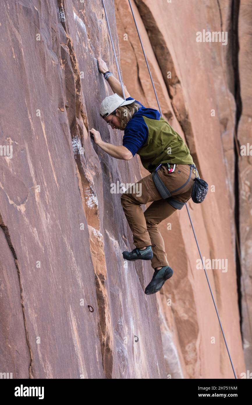 A climber pulls himself up on the Nervous in Suburbia route in the Wall Street climbing area by Moab, Utah. Stock Photo