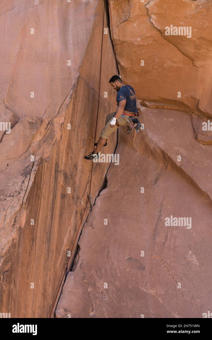 A climber lowers on the rope on the Bad Moki Roof route in the Wall Street climbing area, Moab, Utah. Stock Photo