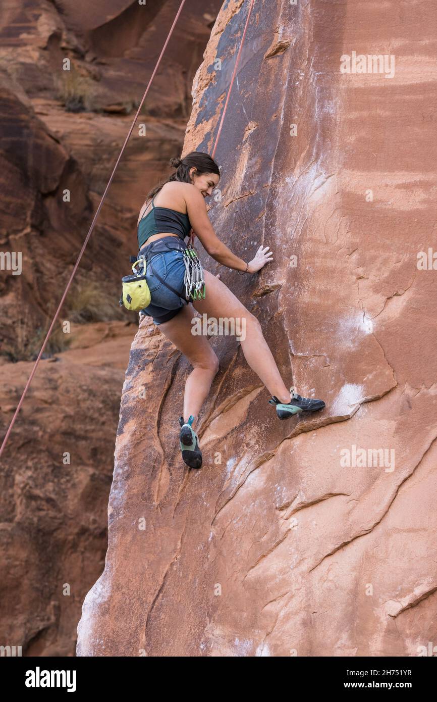 A woman rock climber resting on the rope after falling on a very difficult climb on Wall Street, Moab, Utah. Stock Photo