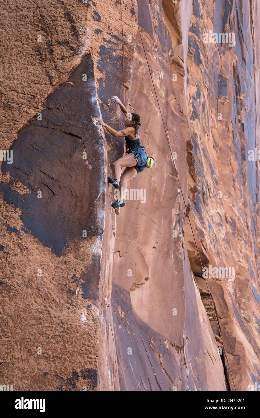 A woman rock climber on the very difficult Under the Boardwalk route on Wall Street, Moab, Utah. Stock Photo