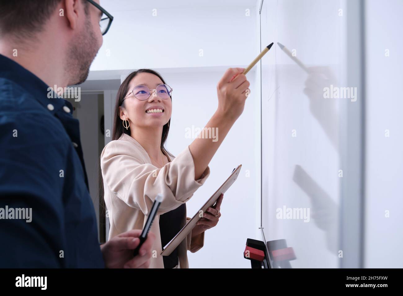 Young asian businesswoman explain a project to her colleague on whiteboard. Stock Photo