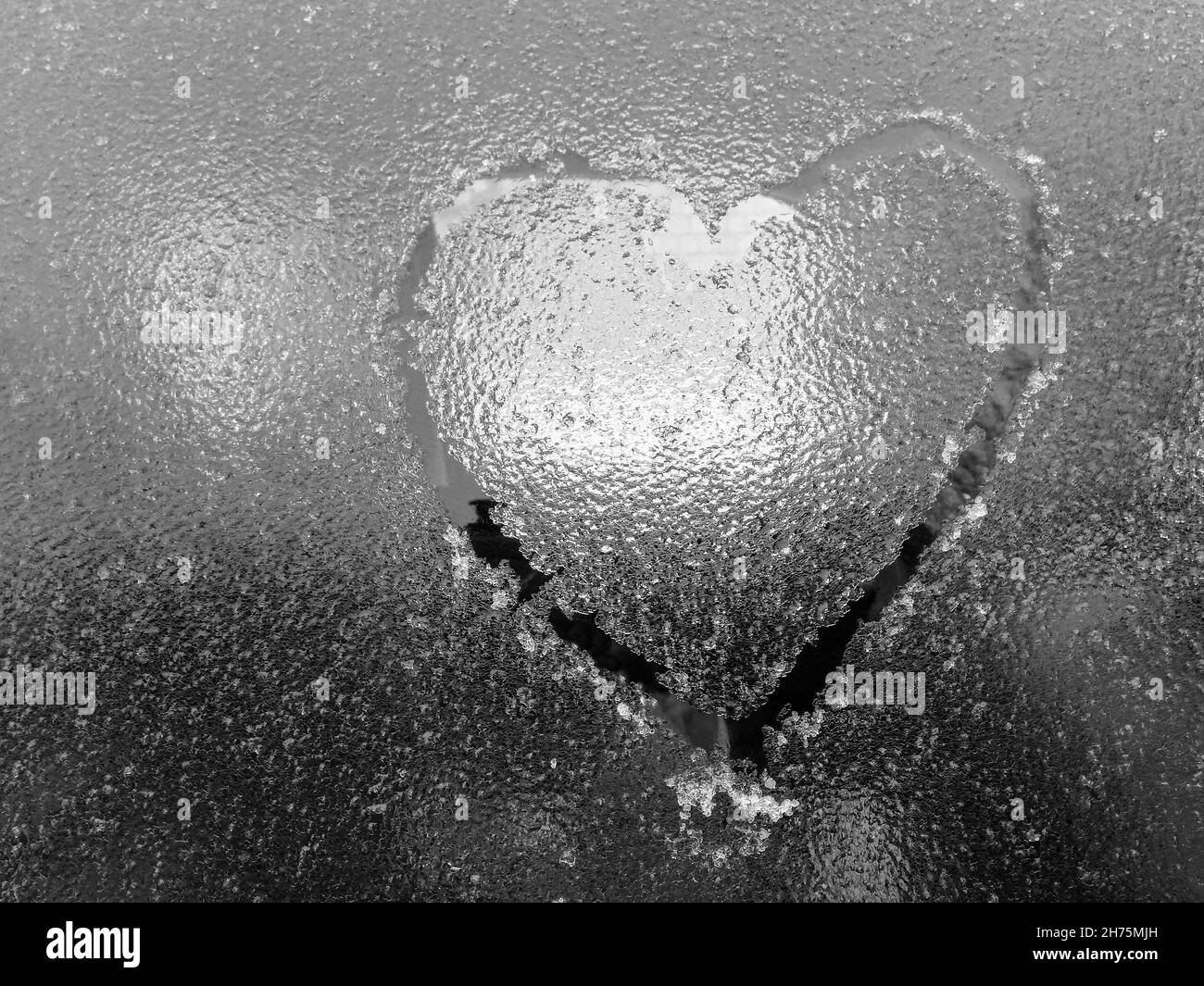 Heart is painted on icy glass window of car. Symbol of love, romance, Valentine's Day. Close-up. Copy space. Selective focus. Stock Photo