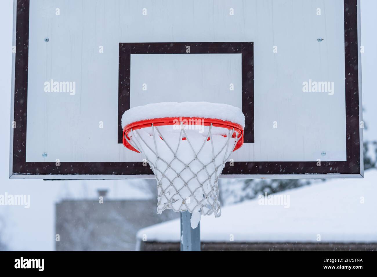 a close up of an orange basketball hoop covered with snow Stock Photo