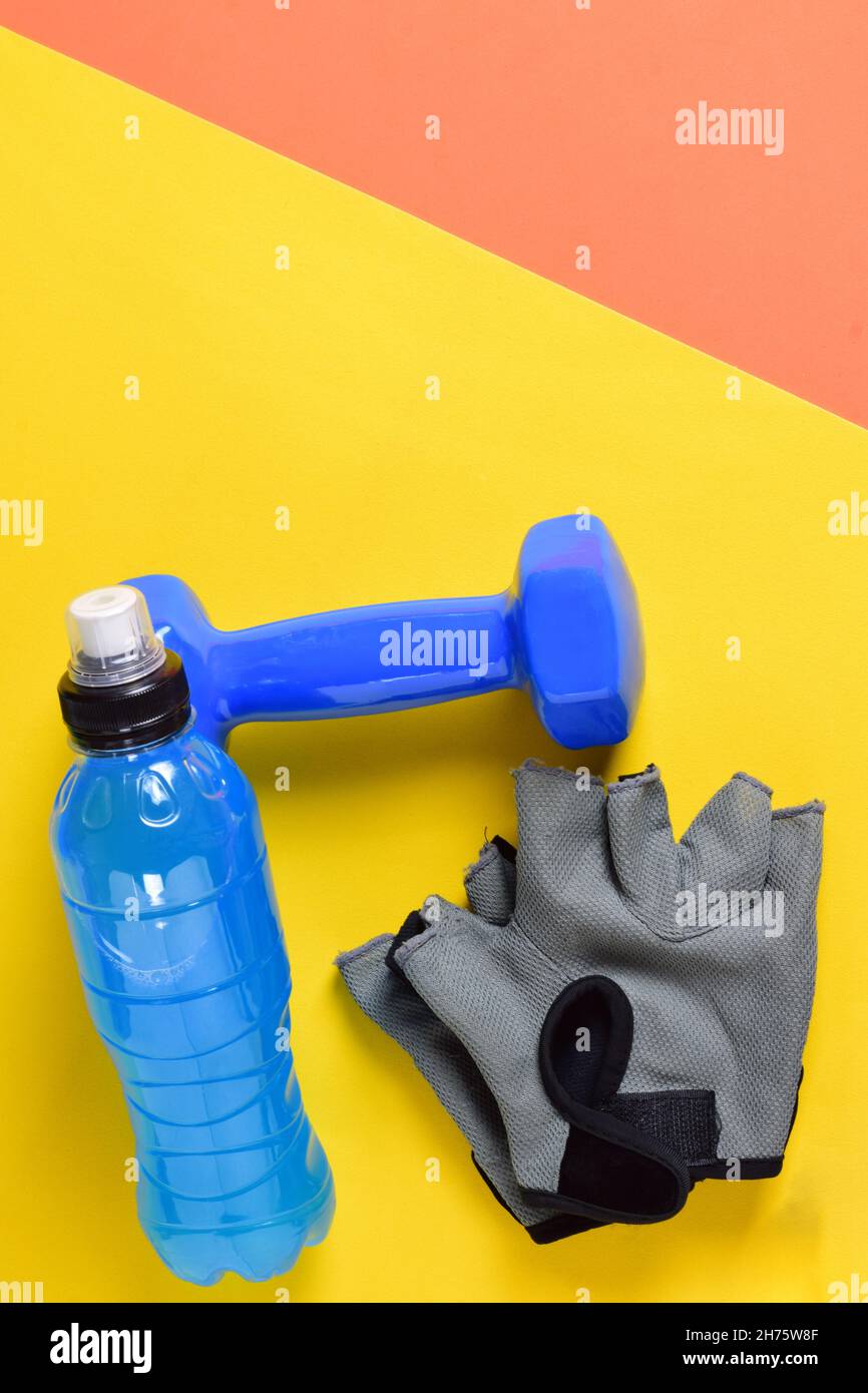 Dumbbell, water bottle, and fitness gloves in the yelloworange