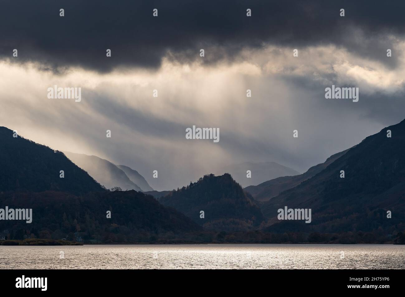 Dramatic light and changeable weather frames Castle Crag and the Borrowdale Valley in the Lake District National Park, viewed across Derwentwater. Stock Photo