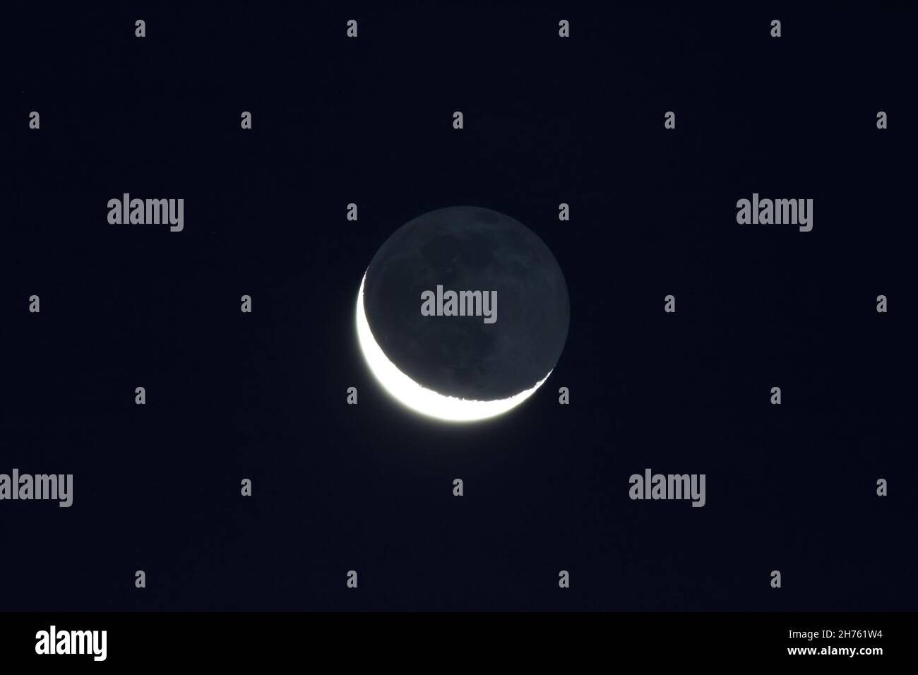 Grey light of waning crescent, moon on dark black sky Stock Photo