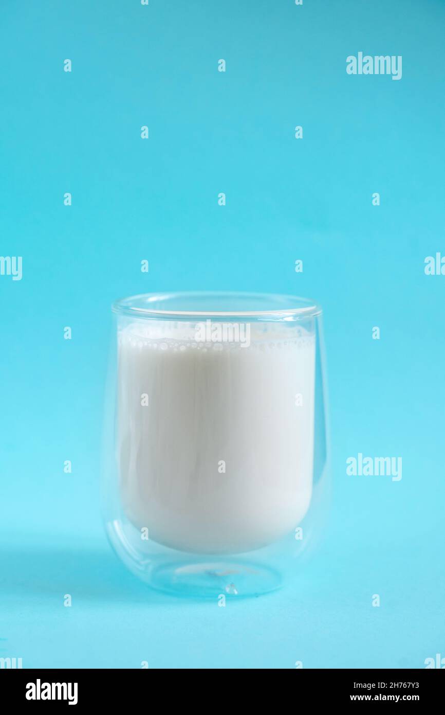Milk in double glass insulate glass on blue minimal background. Lactose free milk made of vegan
