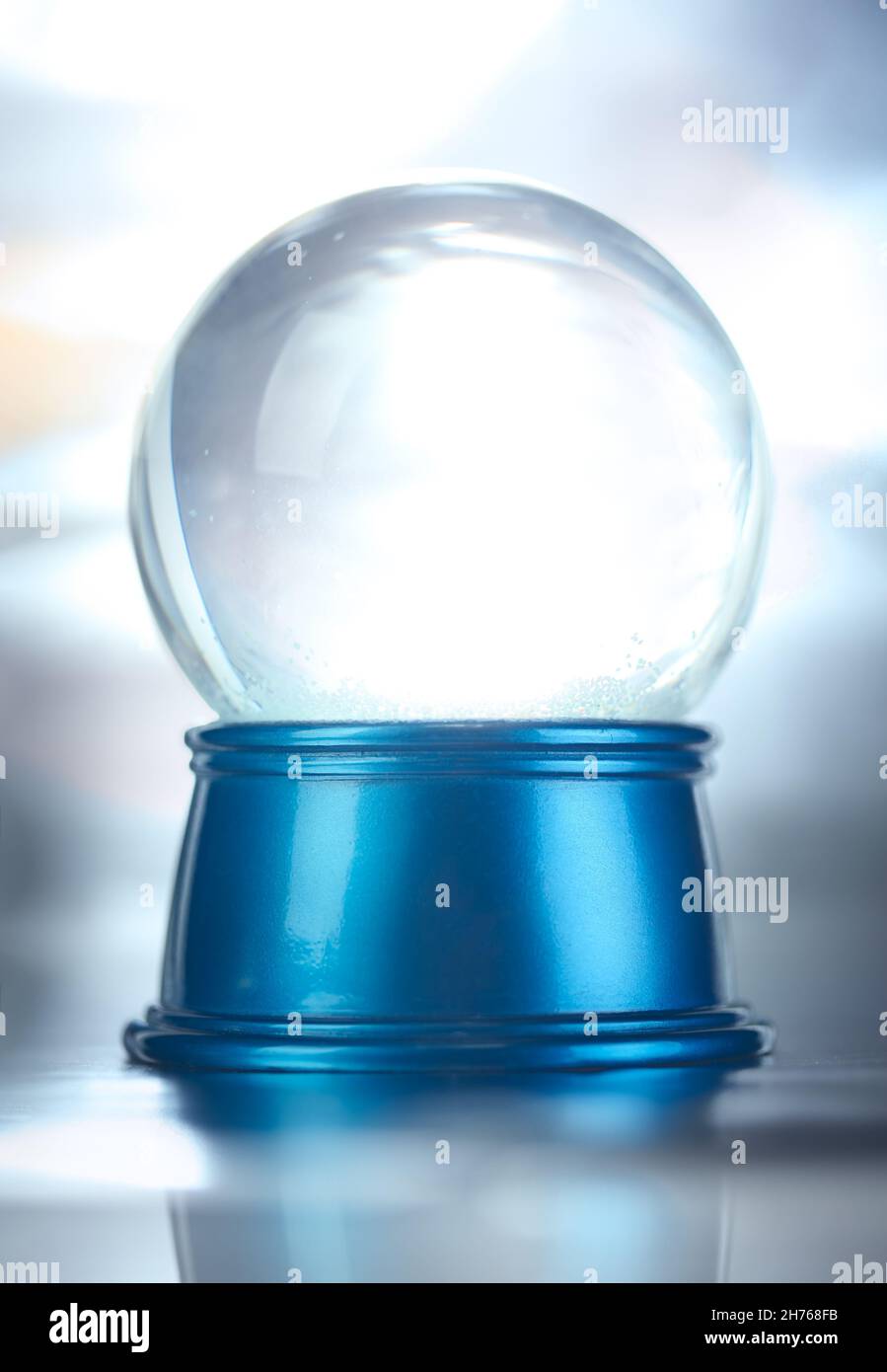 Blank empty snowglobe. Glass snow globe on blue base. Stock Photo