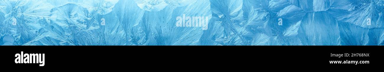 Wintry background with winter frost covered window with a pattern of ice crystals. Stock Photo