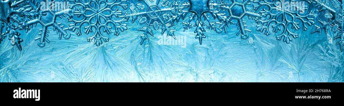 Wintry background with winter frost covered window with a pattern of ice crystals and clear snowflakes. Stock Photo