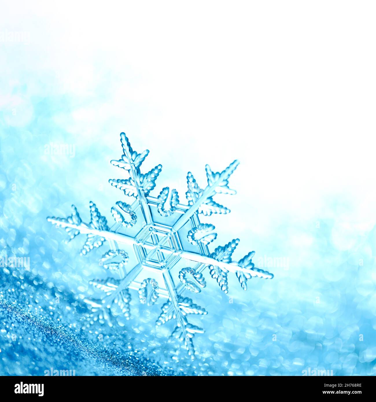 Sparkling blue background with clear shiny snowflake. Stock Photo
